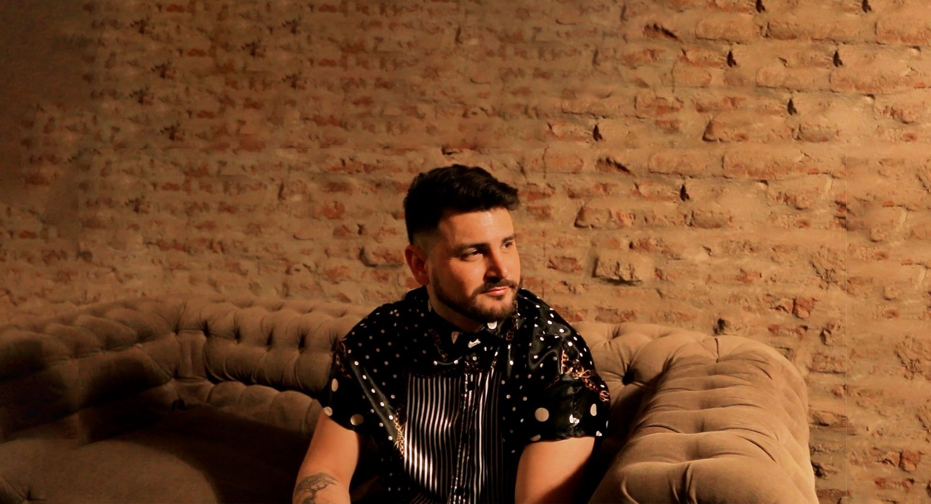 Lisandro Machado, retrato sentado frente a una pared de ladrillos